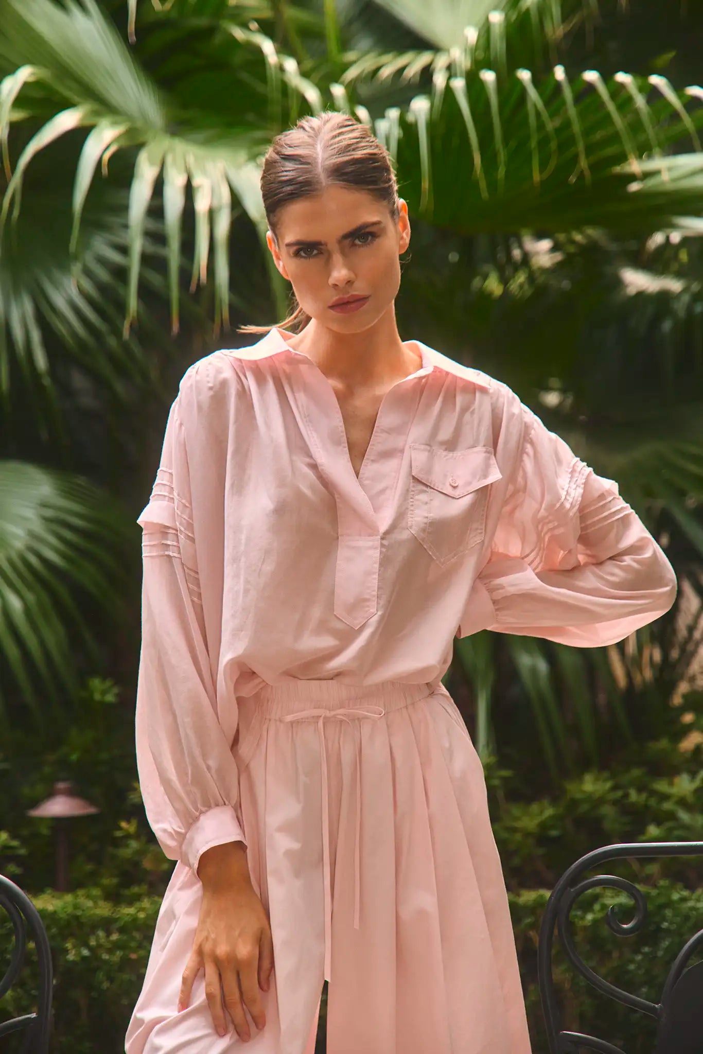 The Evangeline Shirt in Pink Sand paired with the matching Whisper Pant with palm leaves background.