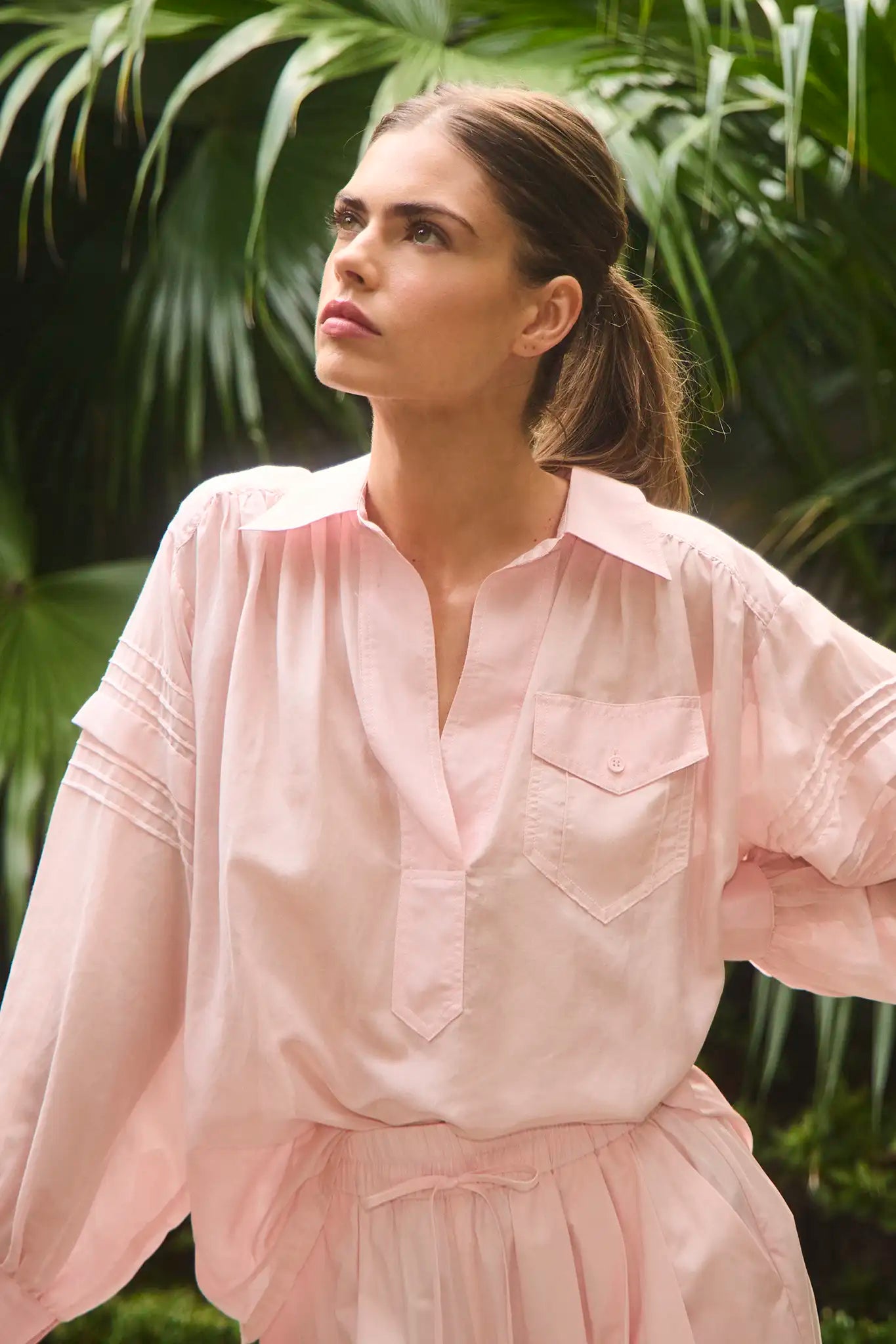 The Evangeline Shirt in Pink Sand paired with the matching Whisper Pant with palm leaves background.