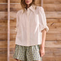 White linen long-sleeve collared shirt with roll-tab sleeves and pearl embellishments.