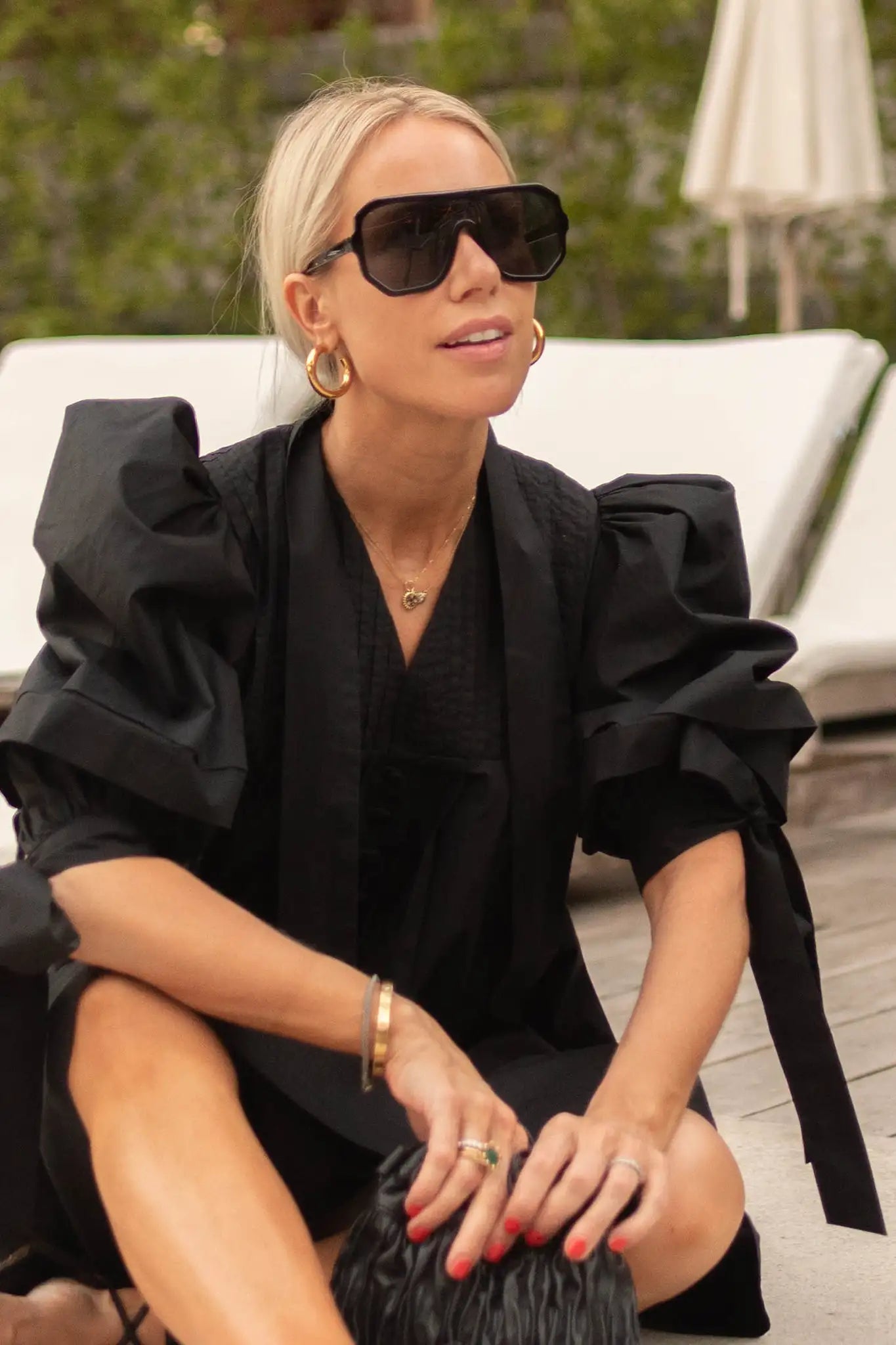 A swingy, V neck black poplin mini dress with elastic cuffs and ties with subtle pleat detailing. 