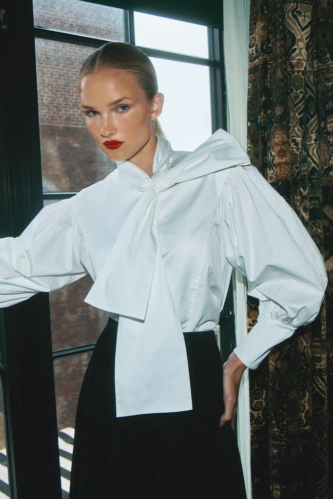 The Shay Blouse is designed with a tie-front neckline and long sleeves with angled button cuffs